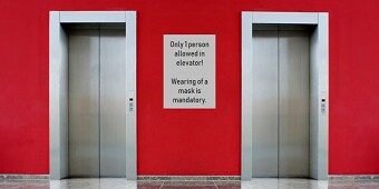 En röd vägg och ett vitt tecken mellan hissdörren
