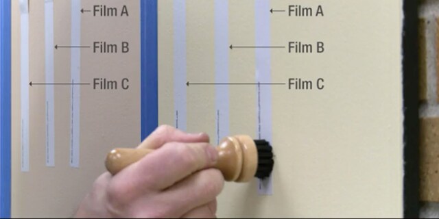 En person håller en suddsvamp i trä på en whiteboard täckt med 3M texturerad väggfolie