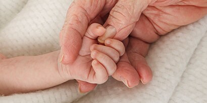 Person som håller babys fingrar
