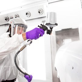 Lackerare applicerar primer på en karossdel med 3M Performance Sprutpistol-system