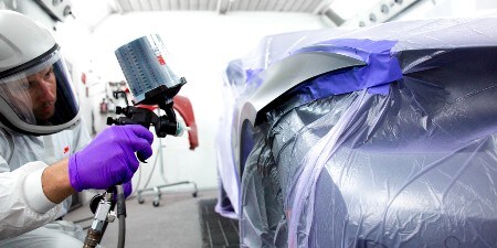 manlig lackerare som lackerar en bil med ett 3M-sprutpistolsystem

