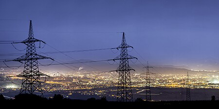 Kraftledningstorn i ett stadslandskap
