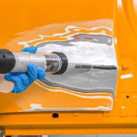 En tekniker applicerar 3M™ FC Epoxispackel för metall för att fylla en buckla