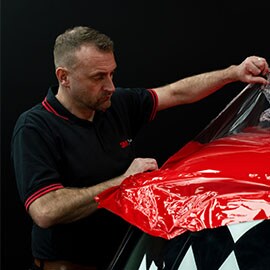Mann som monterer 3M Car Wrap på bilens front