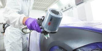 Lackerare sprutar färg på ett område med 3M Performance-sprutpistolen
