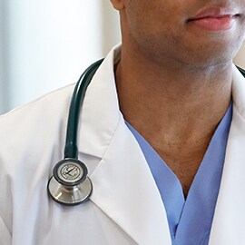 Littmann stetoskop som bärs korrekt utanpå kragen på en vit rock så att slangarna inte rör vid vårdgivarens hals.