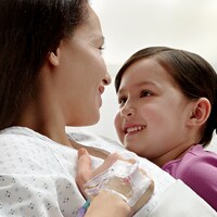Patient in hospital bed with IV secured to her hand