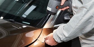 Man som jämför ett färgprovkort med ett billacksområde med 3M Color Check Light II 
