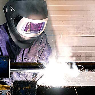 Gnistor flyger när en tekniker svetsar ihop metallsubstrat i en fabrik