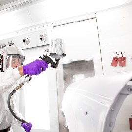 Lackerare applicerar primer på karossdel med 3M Sprutpistol-system