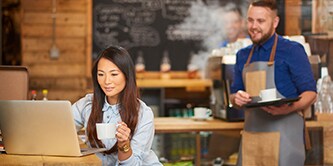 Kvinna som sitter på ett café och arbetar på sin bärbara dator
