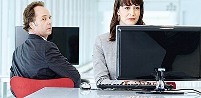 En visuell hacker kikar över hans axel på en bildskärm
