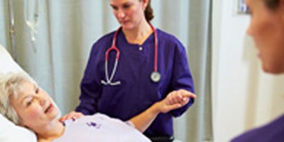 En sjuksköterska tittar till en äldre patient
