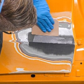 En tekniker applicerar ett andra lager 3M™ FC Epoxispackel för metall för att fylla bucklan 